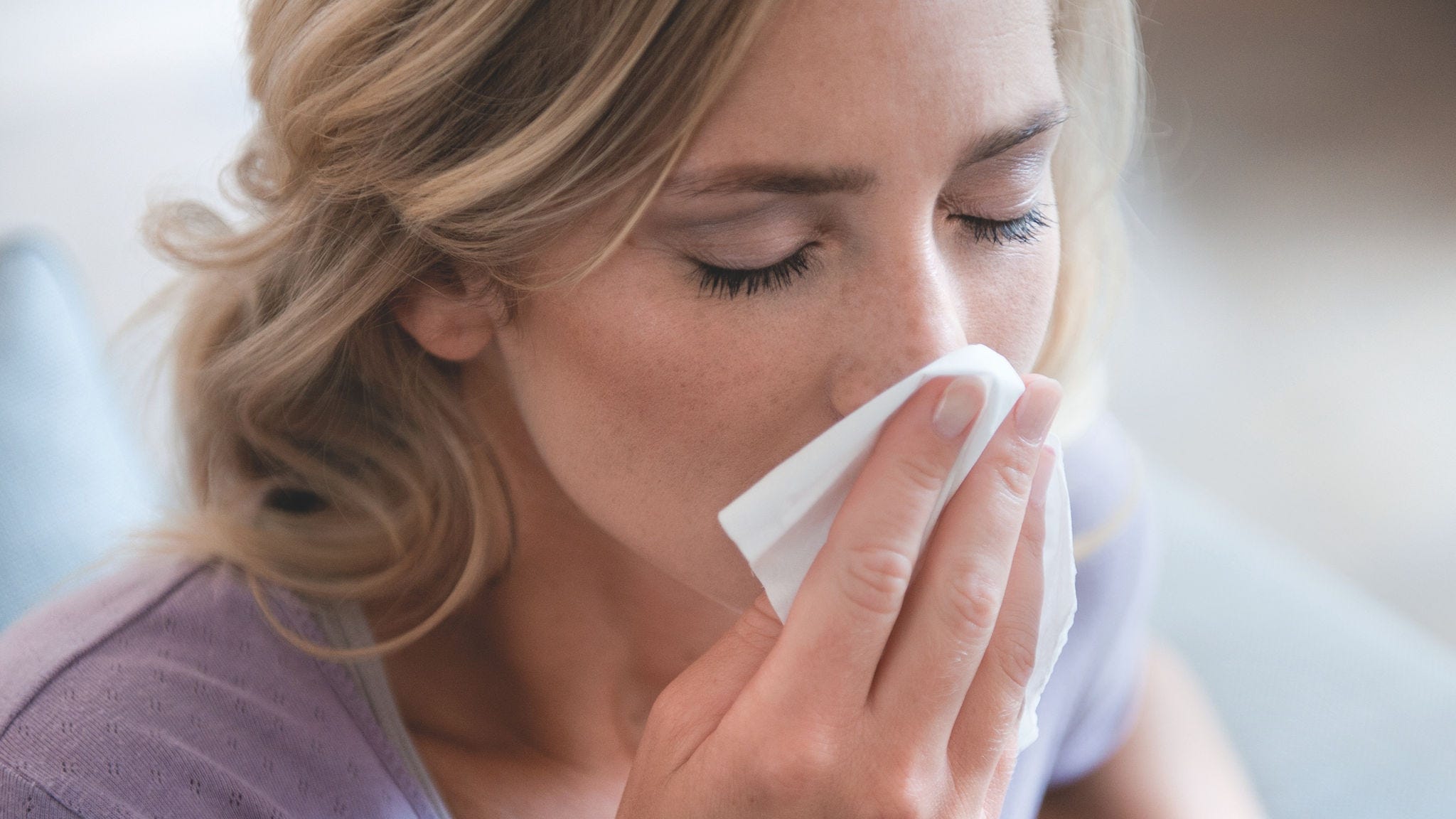 A pollenallergia miatt az orrát fújó nő