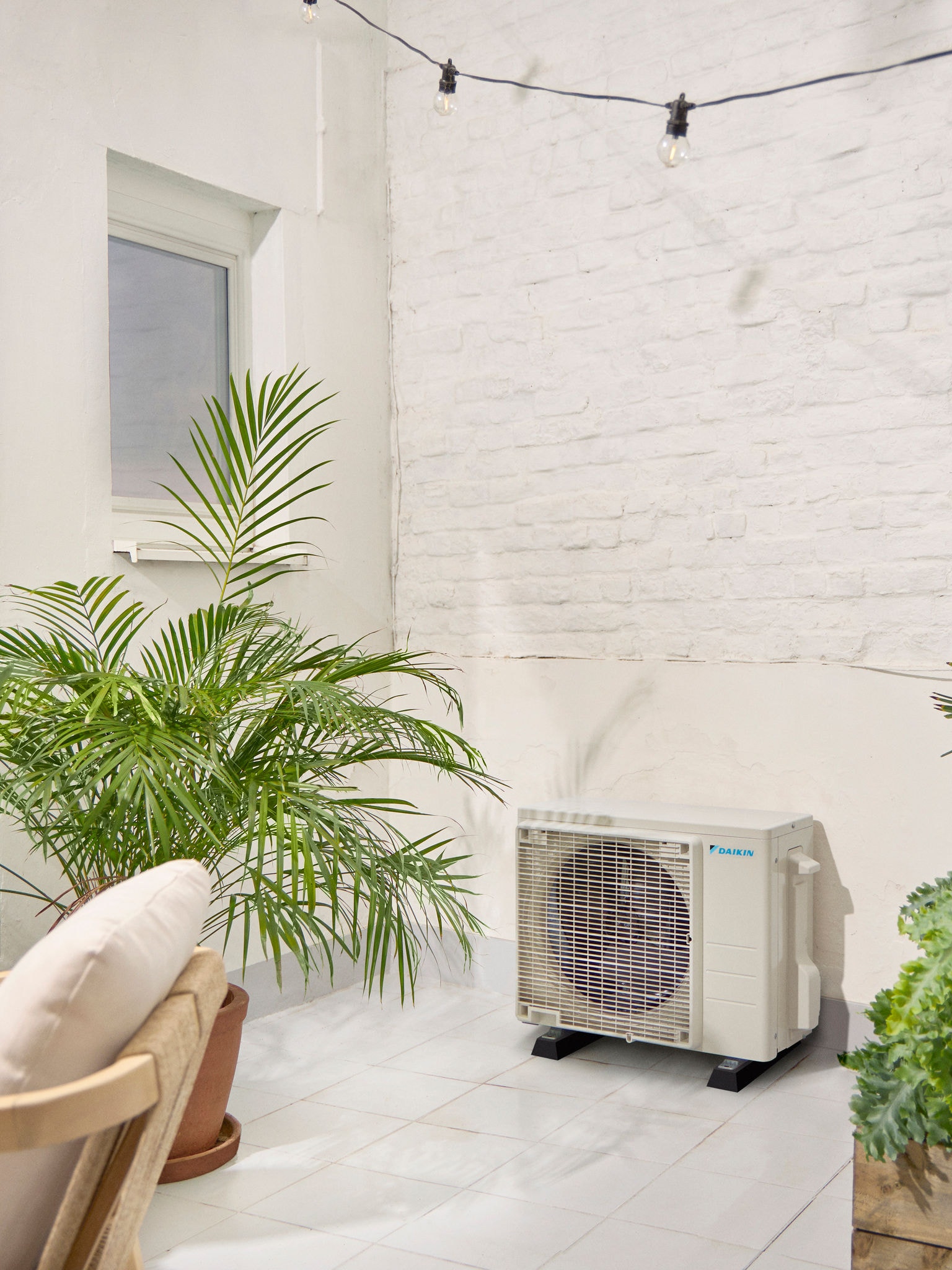 Daikin kültéri egység a fehér teraszon egy növénnyel