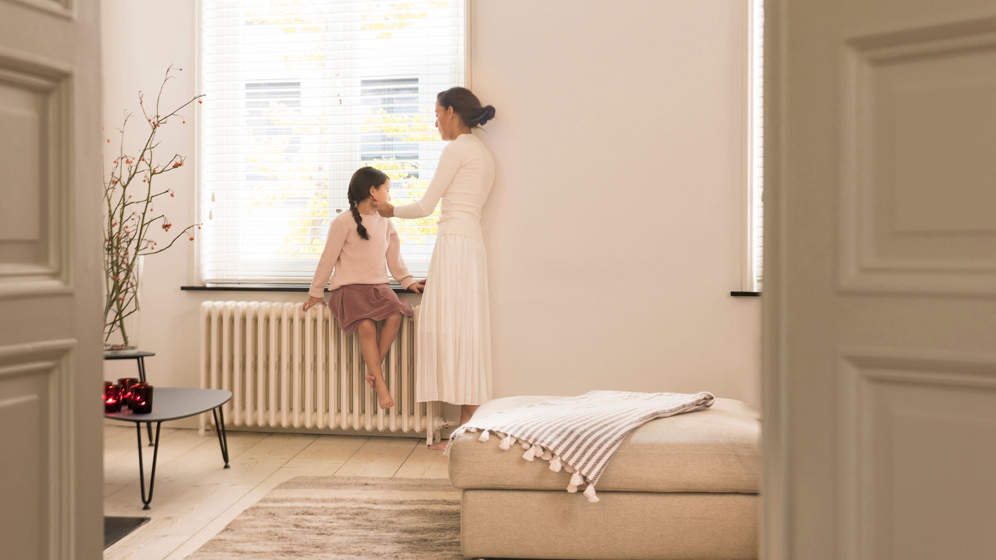 Anya és lánya kinéz a tökéletesen fűtött nappalijuk ablakán