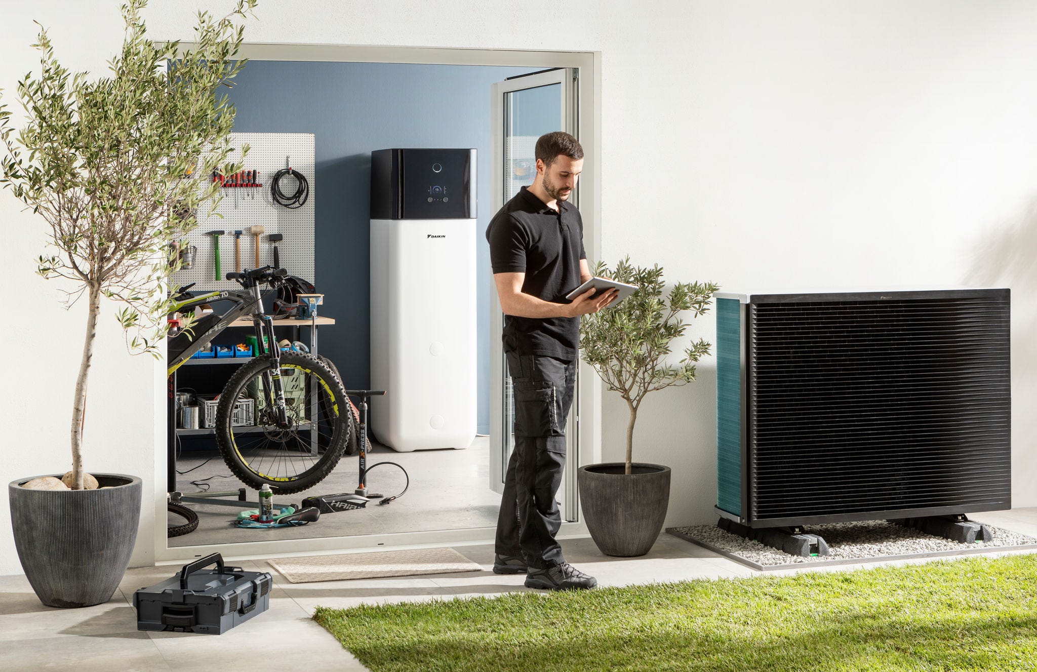 A telepítő szakember ellenőrzi a levegő-víz hőszivattyú kültéri egységet és a melegvíz-tartályt