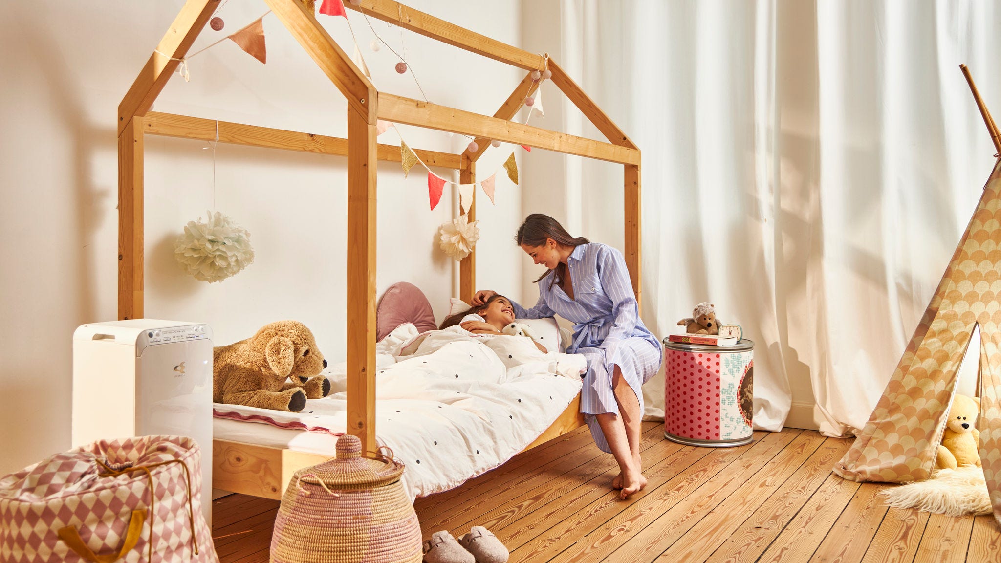 Anya ágyba teszi gyermekét a Daikin légtisztító miatt egészséges otthonukban lévő gyermekszobában