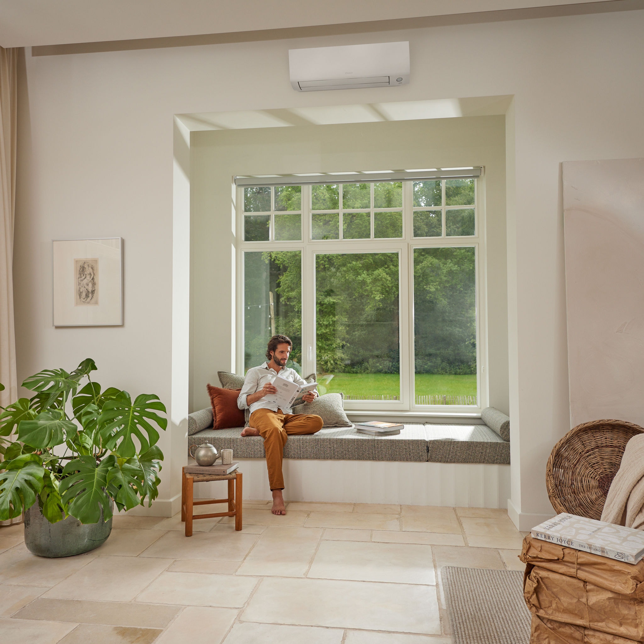 Man relaxing reading the paper while sitting on the window seat in his air conditioned living room