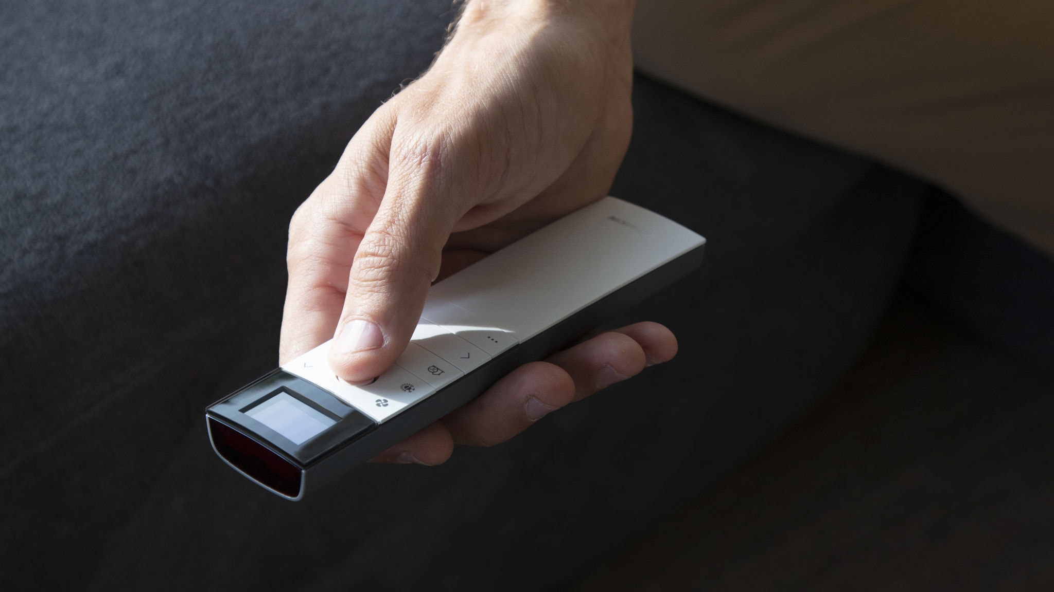 Egy férfi a nappaliban szabályozza a klímát a távirányítóval