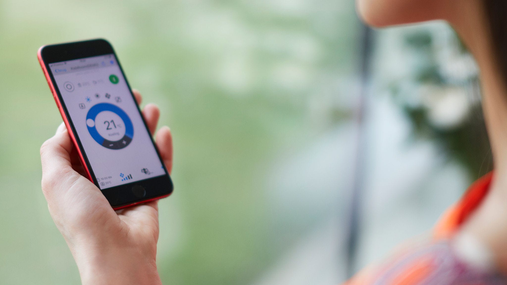 Egy nő az alkalmazást használja a fűtés szabályozására