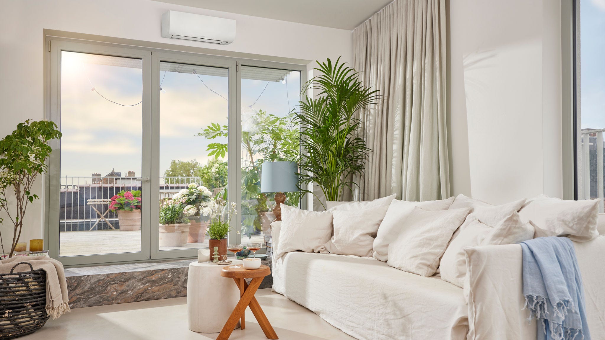 Világos, tágas szoba, amelyben egy diszkrét, fehér, oldalfali klíma biztosítja a fűtést és a hűtést