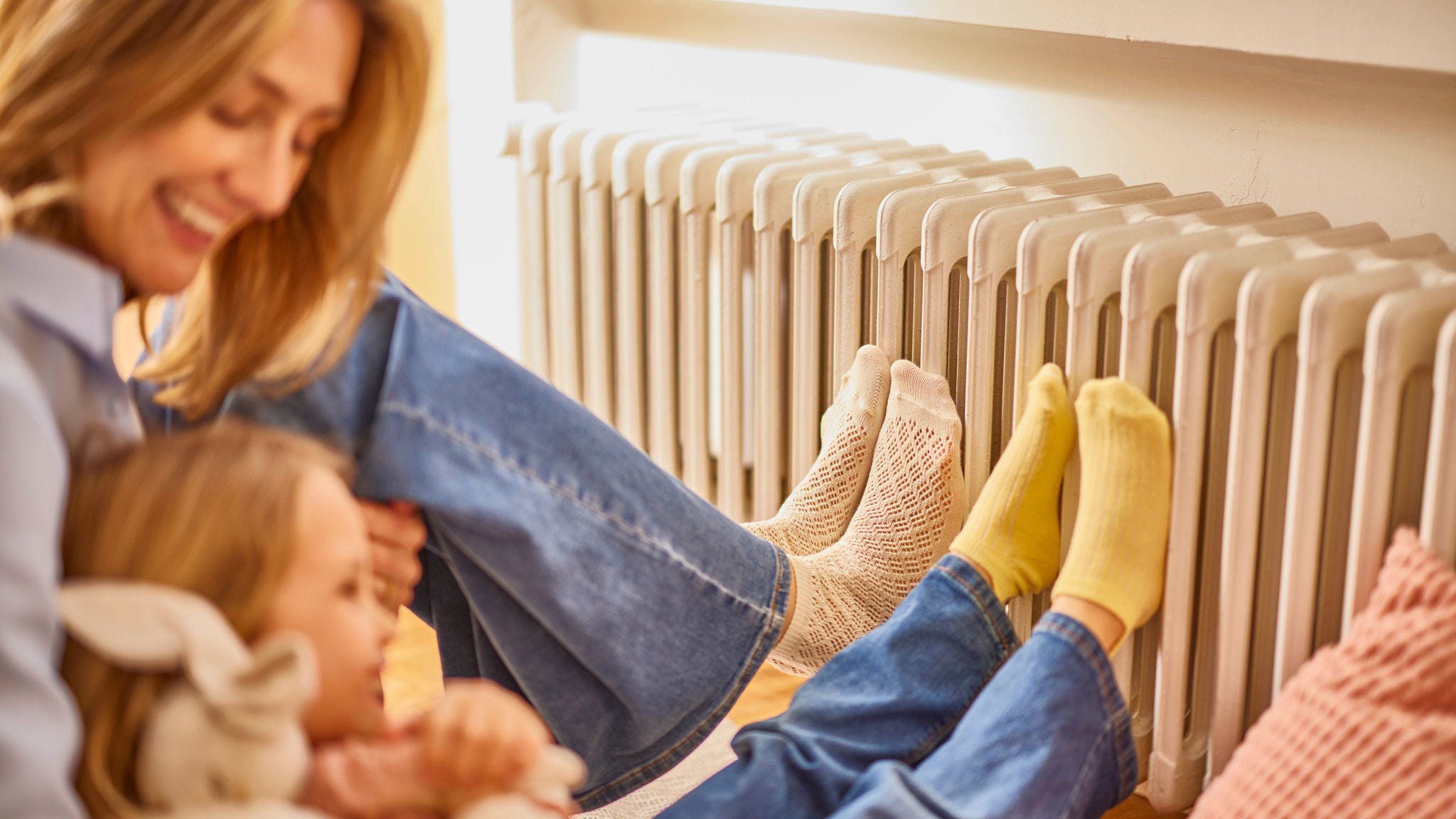 Anya és lánya melegítik a lábukat egy radiátoron a meleg és kényelmes otthonukban