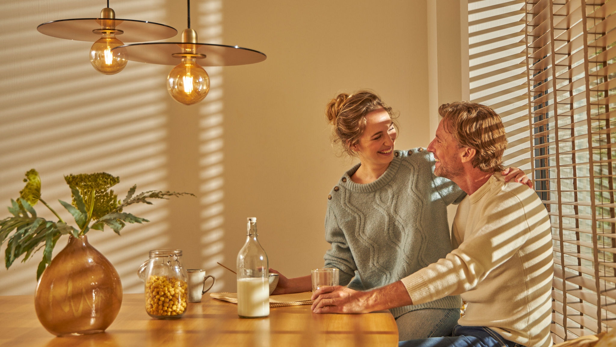 Egy pár élvezi a kellemes reggelit együtt a kényelmes, meleg konyhában, az intuitív fűtési technológiának köszönhetően