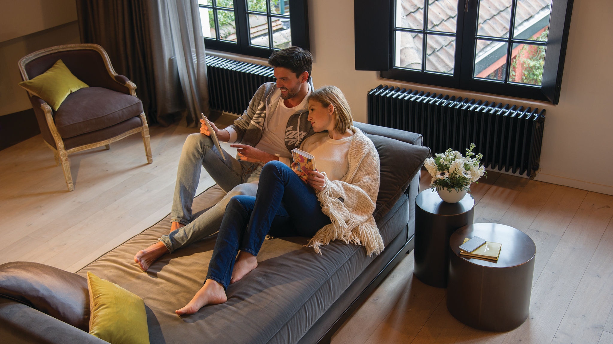 Egy pár relaxál egy kanapén és valamint néznek a tabletükön