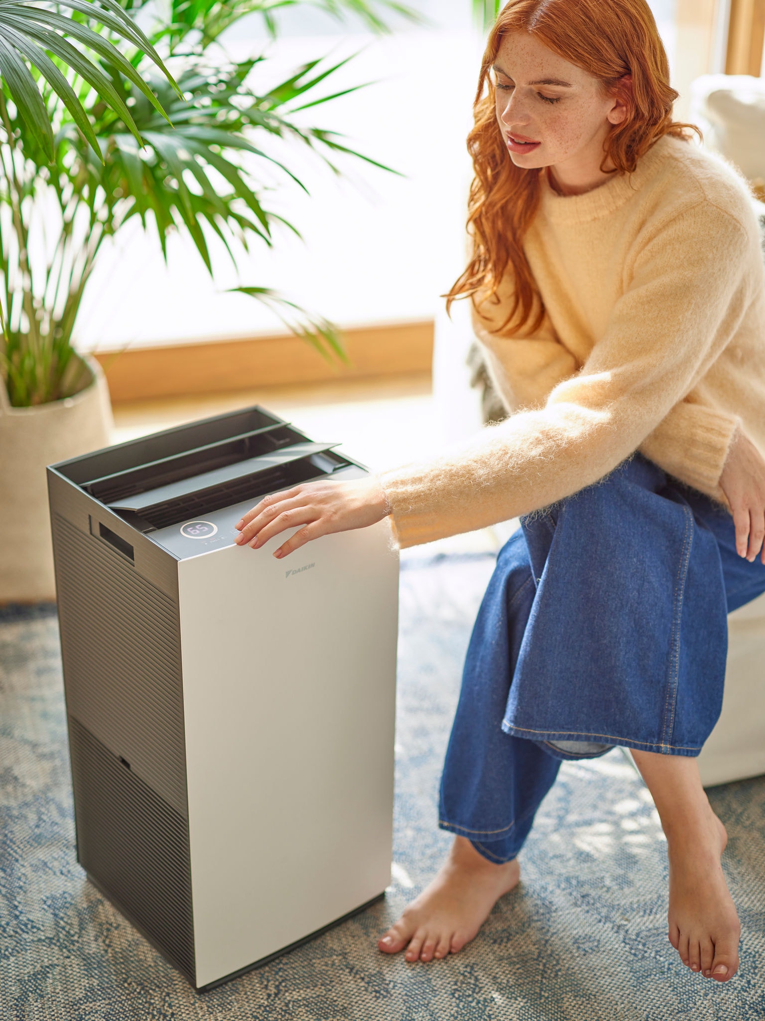 A nappaliban egy nő a Daikin légtisztító vezérlőjét állítja be