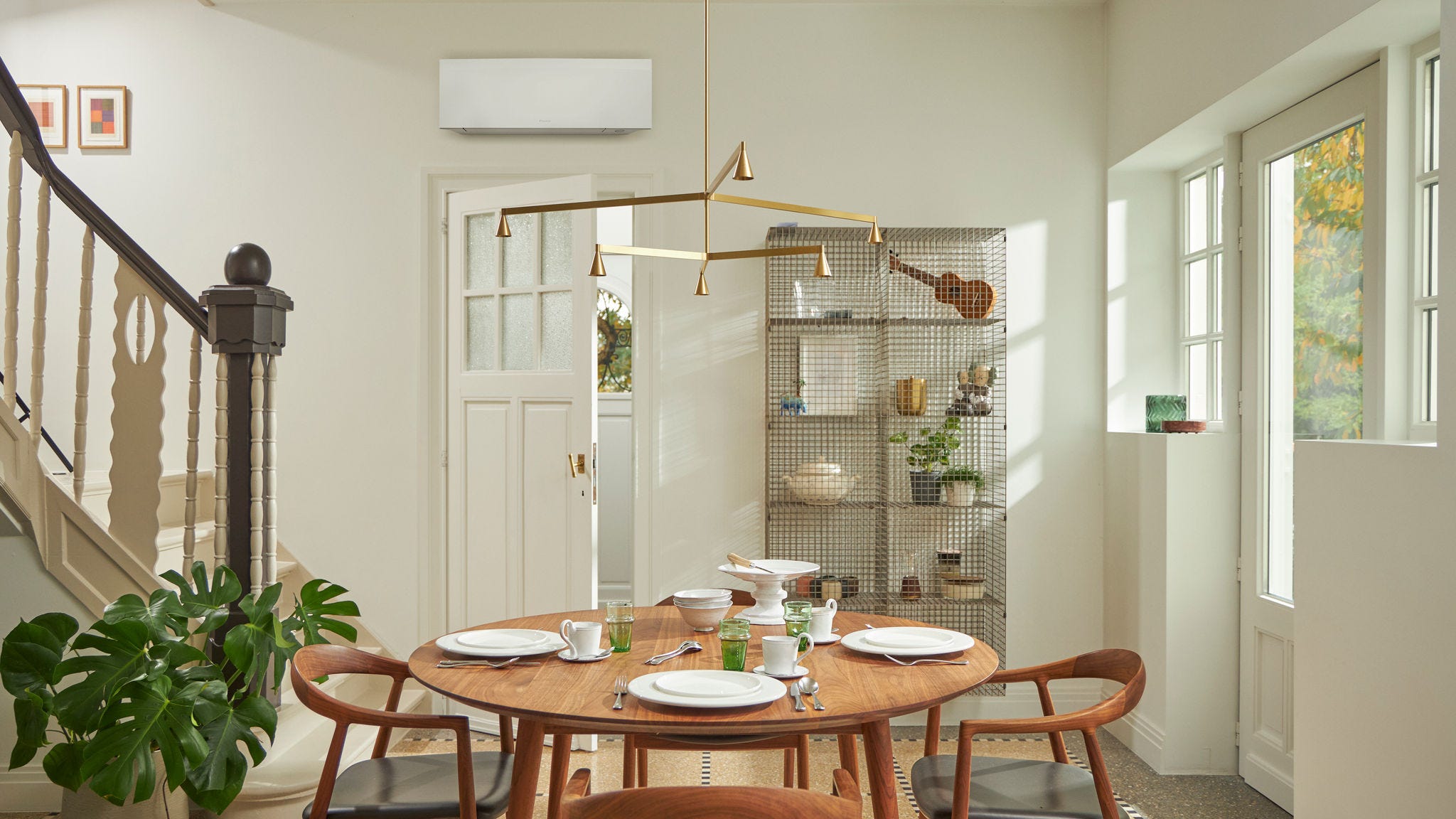 Szoba nagy ablakkal, fa asztallal, és fekete, oldalfali klímamegoldással