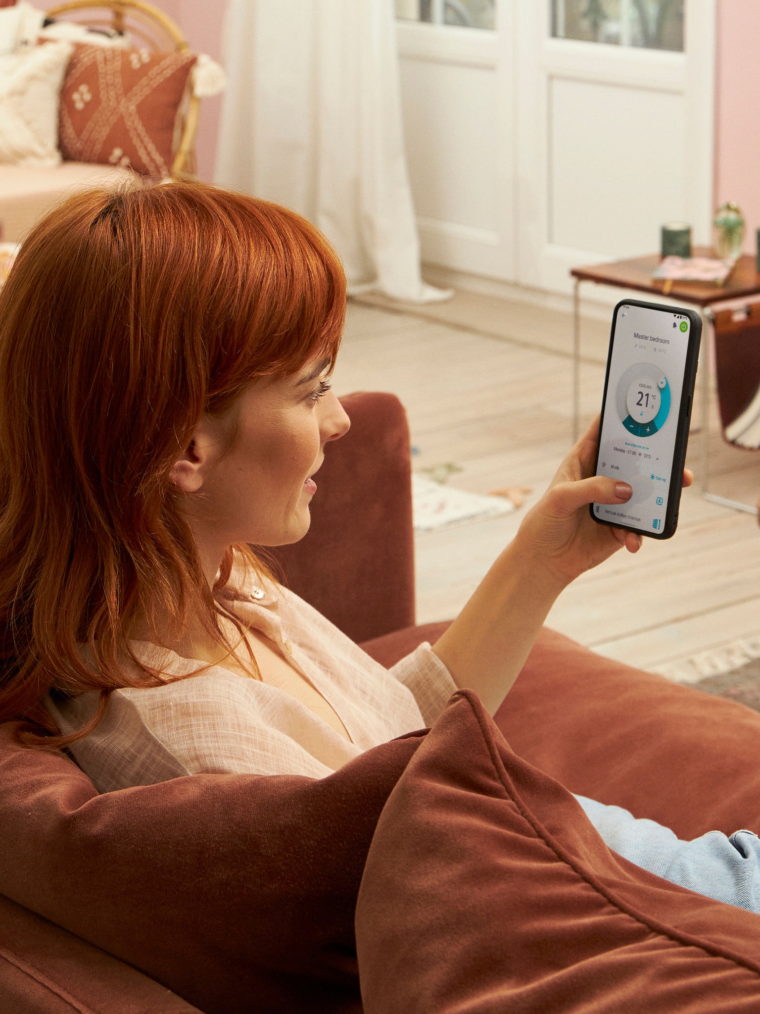 Egy hölgy az egyes beltéri egységeket külön szabályozza az Onecta alkalmazással